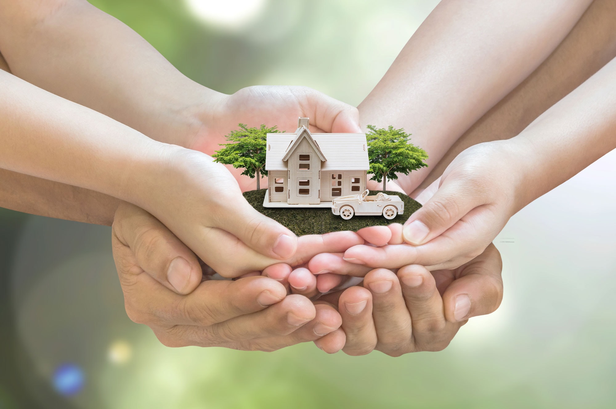 Multiple hands holding a miniature house and car, symbolising family trust and shared property ownership