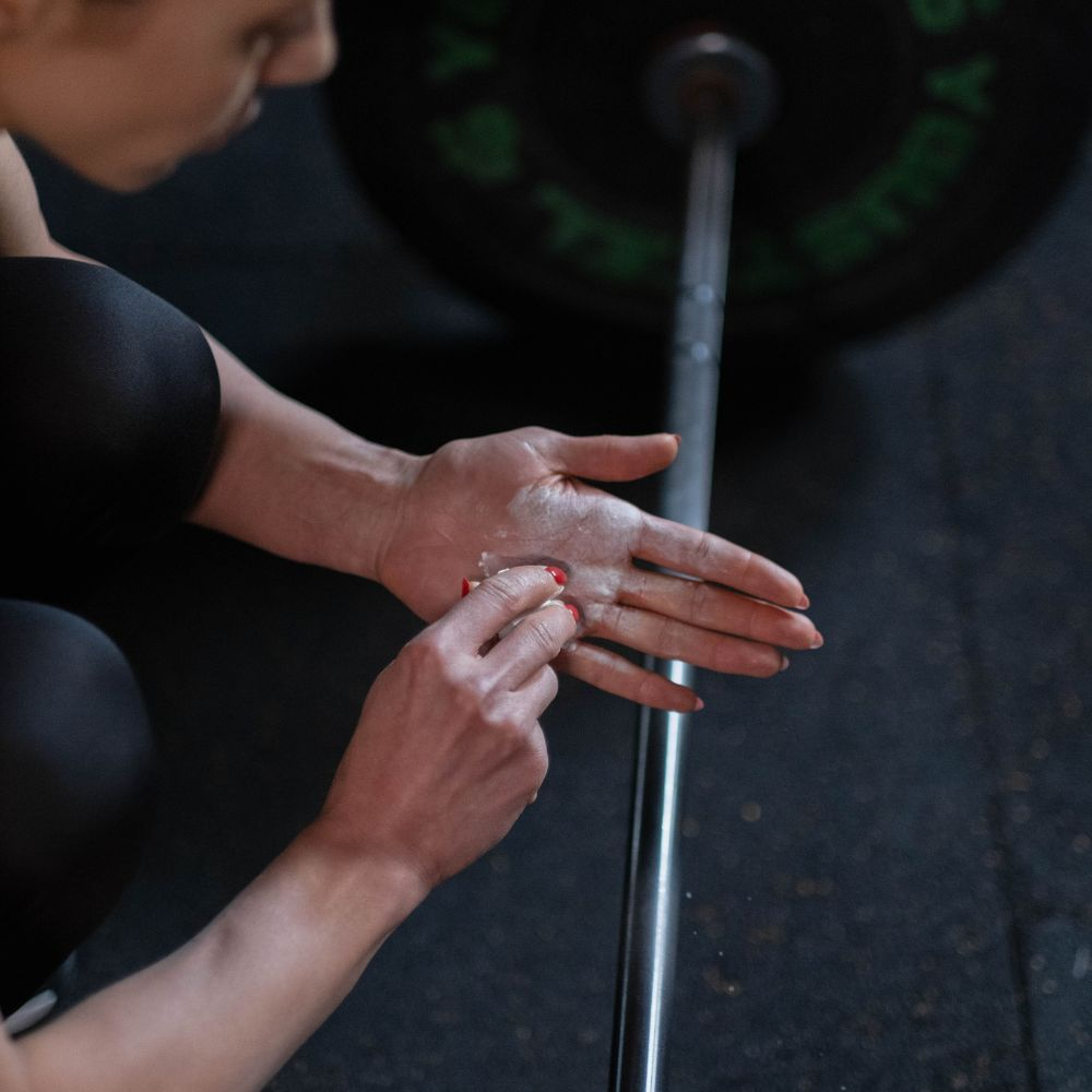 A person using gym chalk to improve grip on a barbell