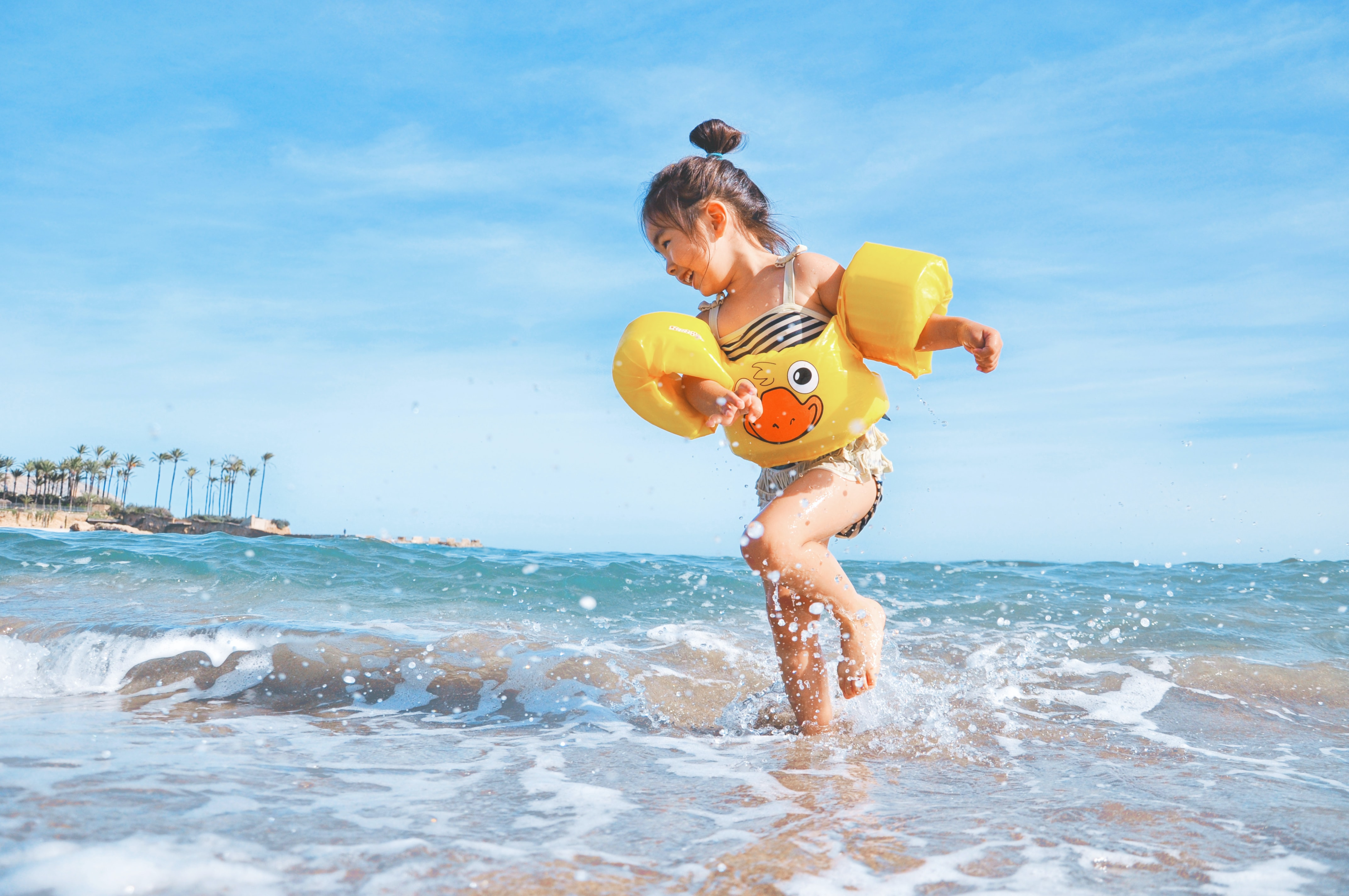 girl with water-wings playing in the waves at the beach