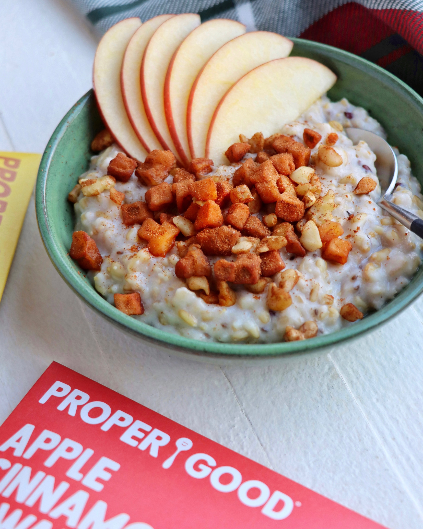 Delicious bowl of Proper Good's Apple Cinnamon & Walnut Oatmeal topped with fresh sliced apples