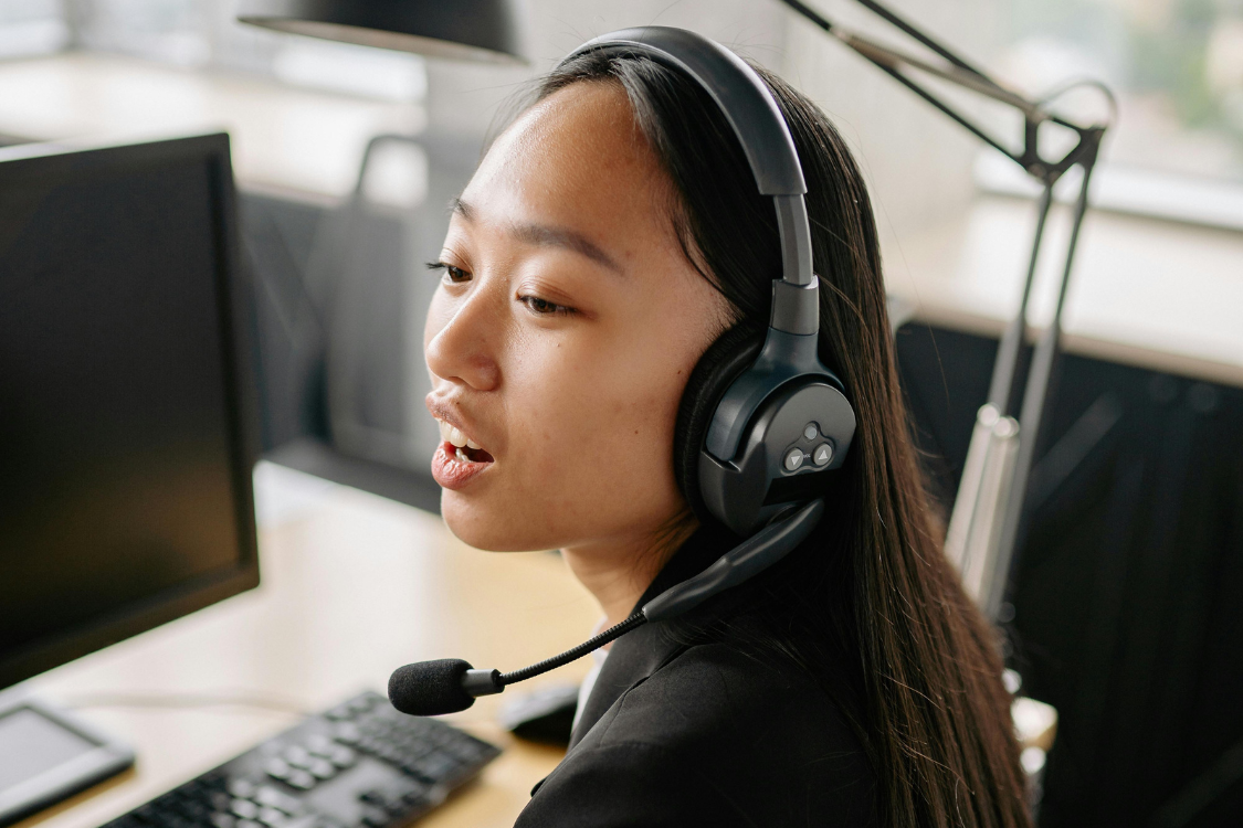 Filipino remote worker speaking with a client while wearing a headset in a home office setup