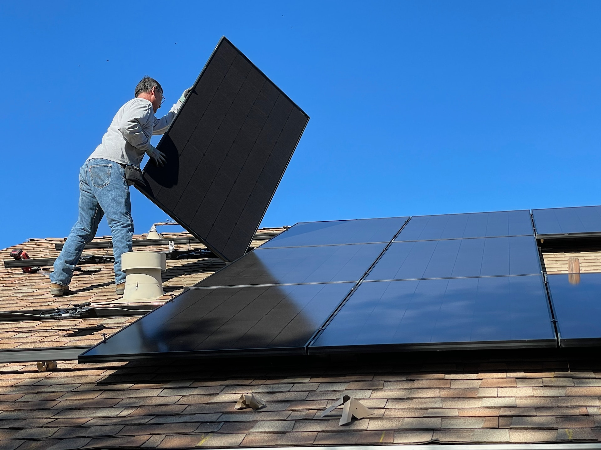 A homeowner installing solar panels, by himself, on the roof of his house.  