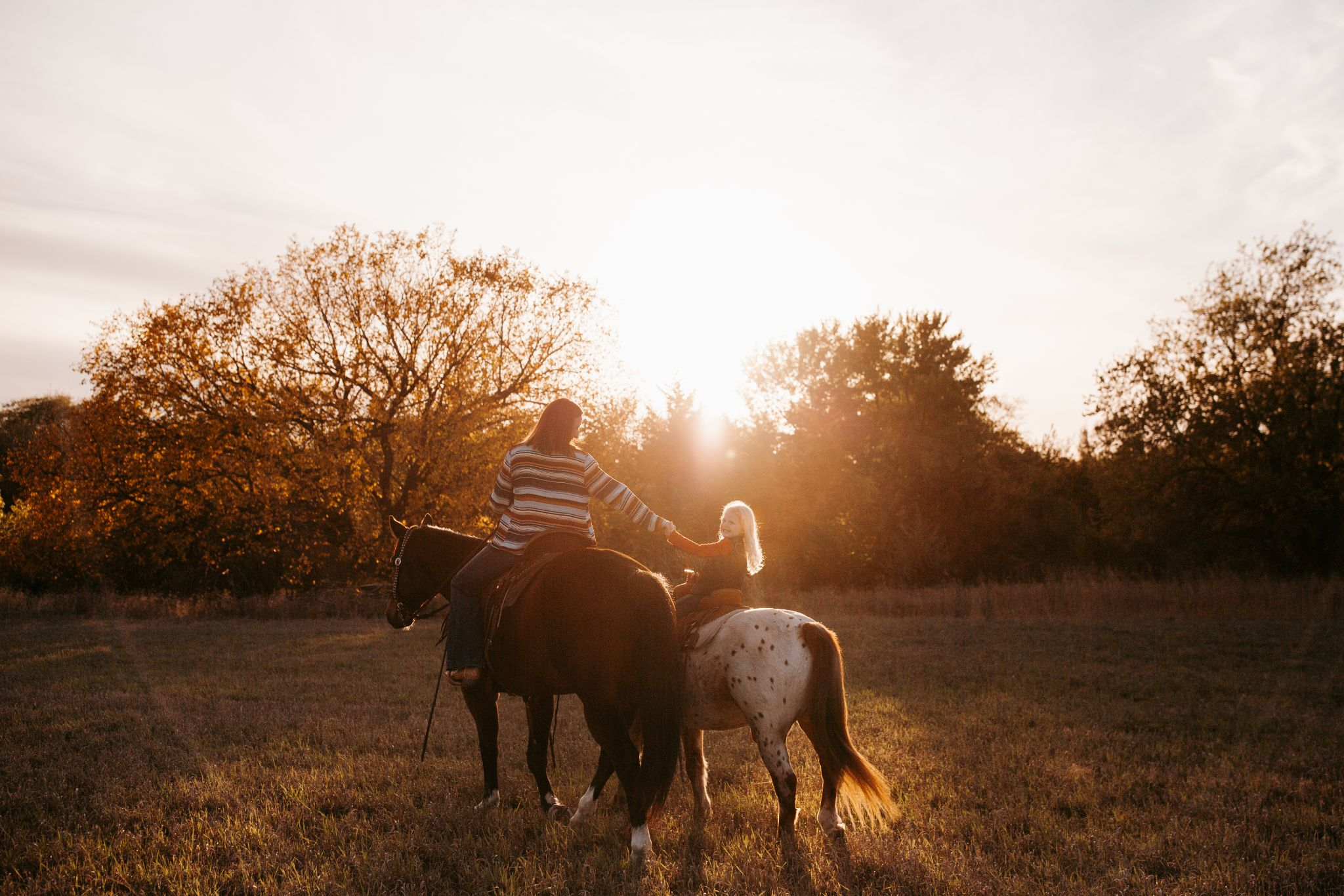 Child and person on horseback with two horses