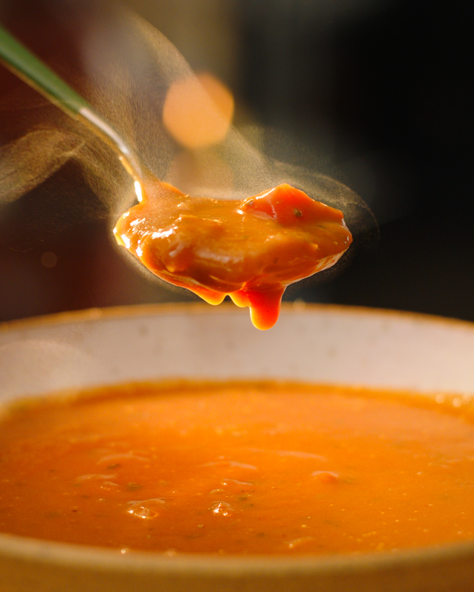 A bowl of Proper Good's Tomato Basil Soup with a spoon