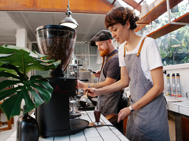 Baristas preparam café em máquinas. Foto: Tim Douglas de Pexels - Canva.