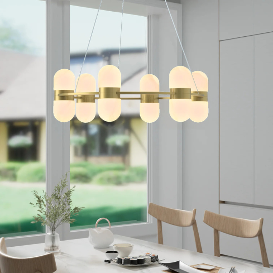 Modern gold chandelier with frosted glass oval shades hanging above a dining table in a bright contemporary dining room.