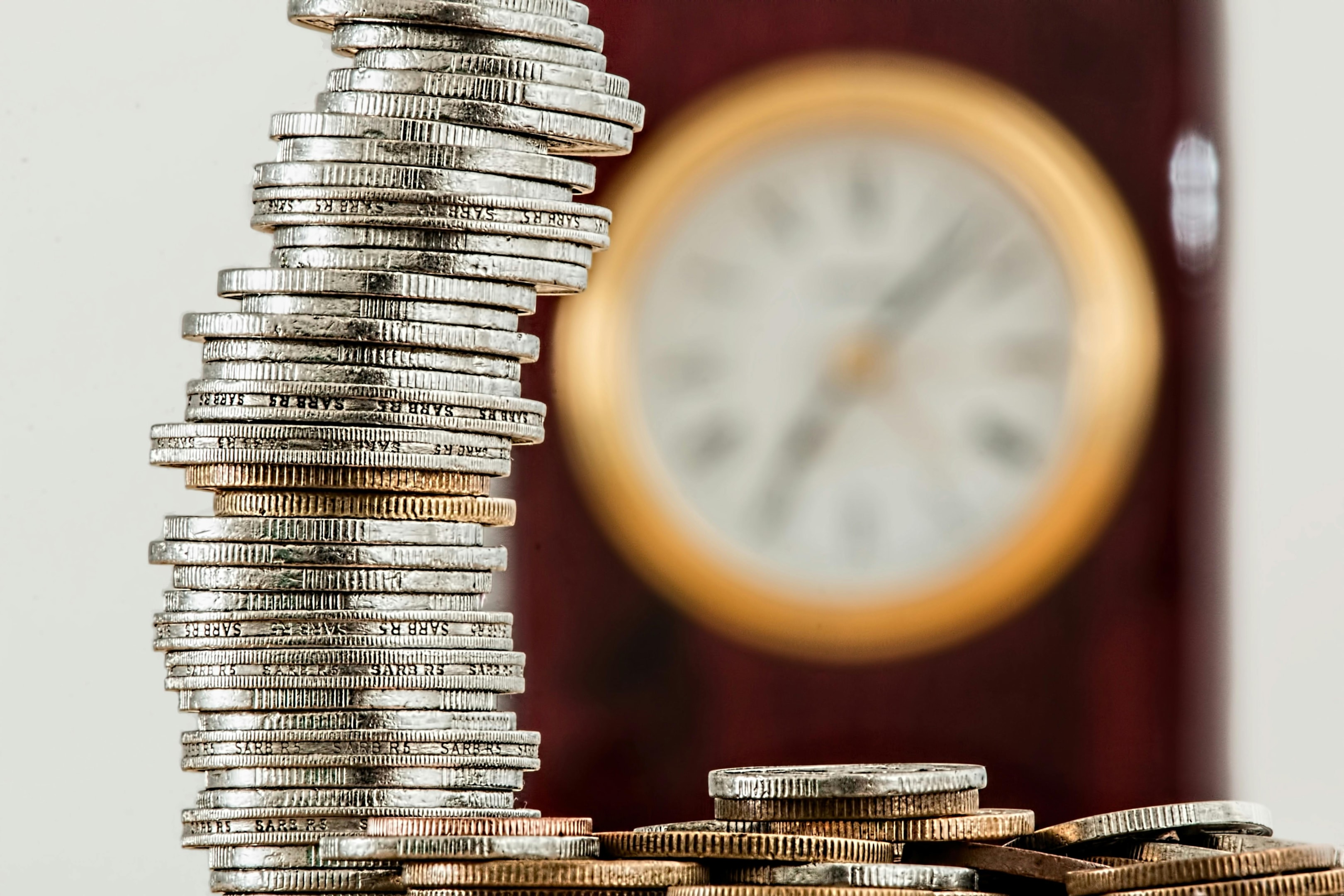 Coins stacked in front of clock. 