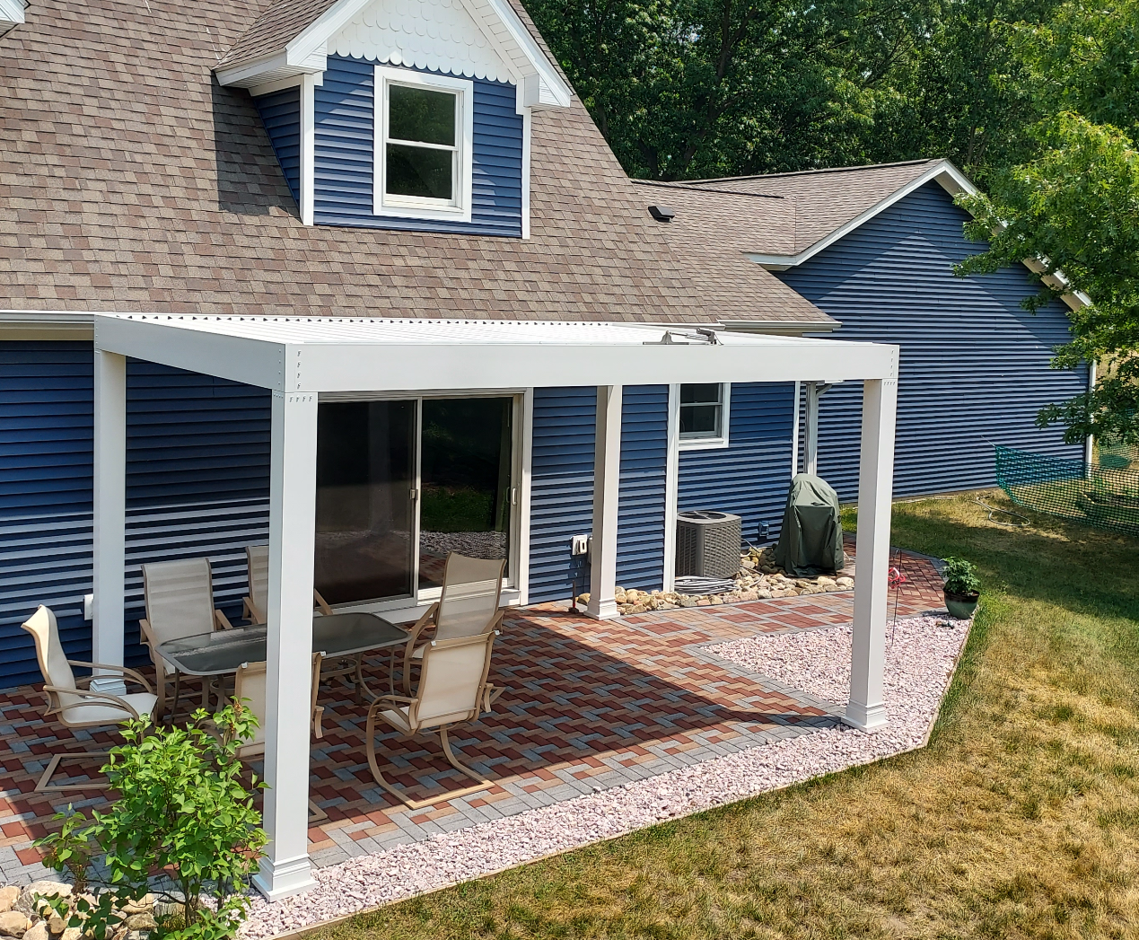 blue house with white luxury pergola complimenting the  back patio