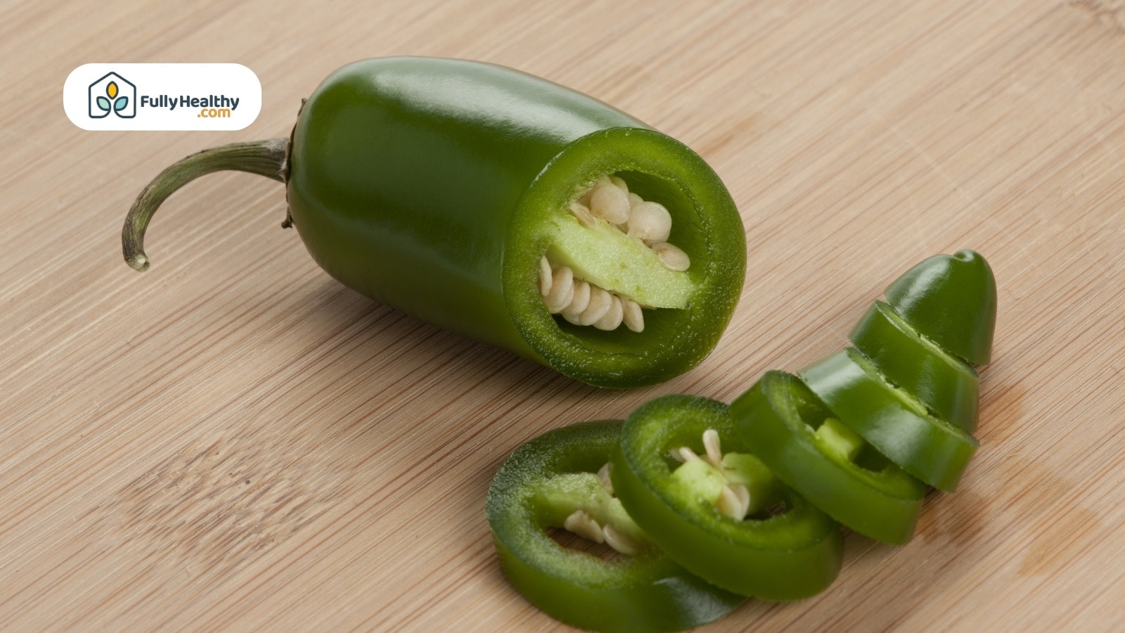 Whole and sliced jalapeño on wooden surface showing seeds inside