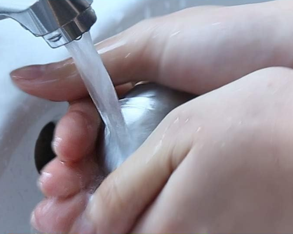 A person cleansing their hands with a metal stainless soap bar
