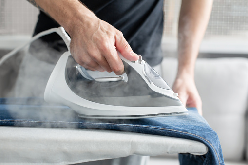 Crop person ironing jeans