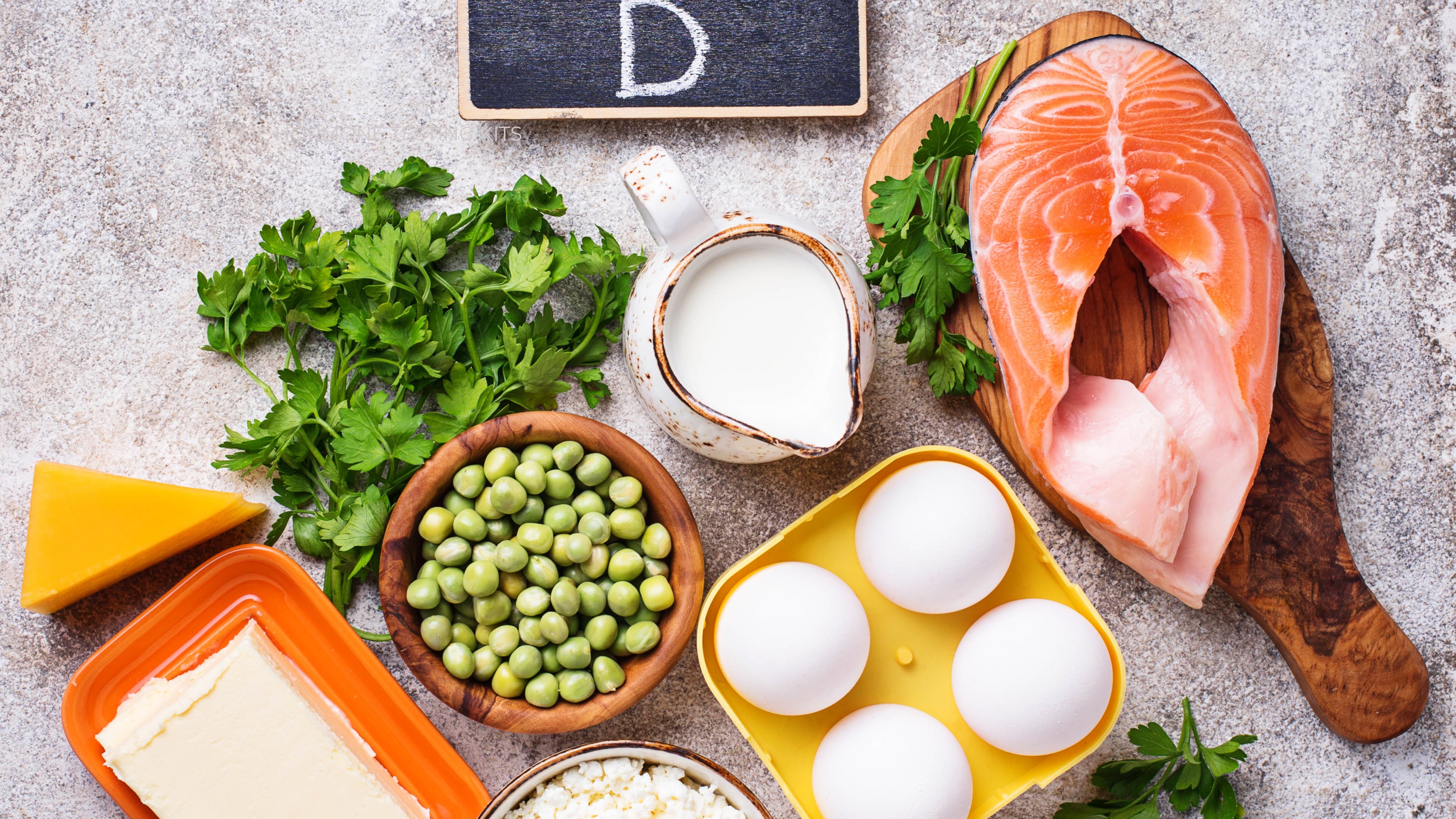 Food displayed on a table showcasing food groups that are rich in vitamin D- such as salmon, eggs, cheese, beans and milk
