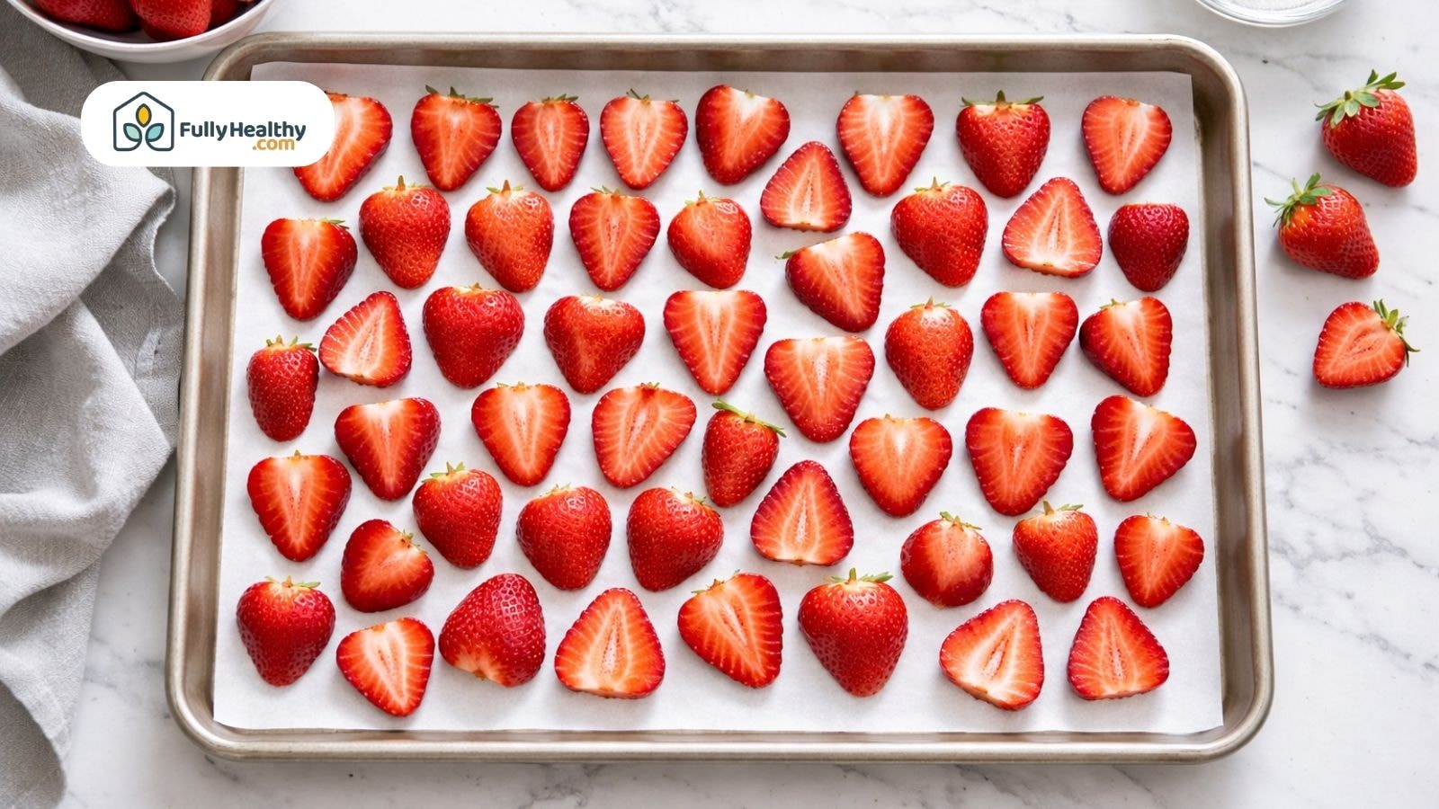 Sliced strawberries on parchment-lined tray ready to flash freeze