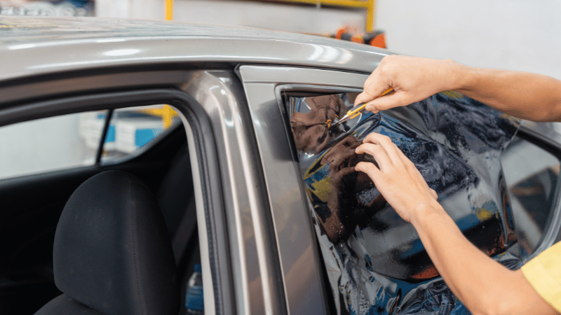 A man is cutting the car window tint film.