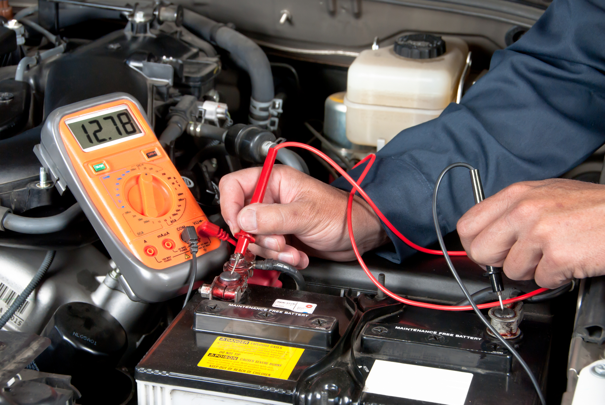 Technician is checking battery voltage with multimeter.