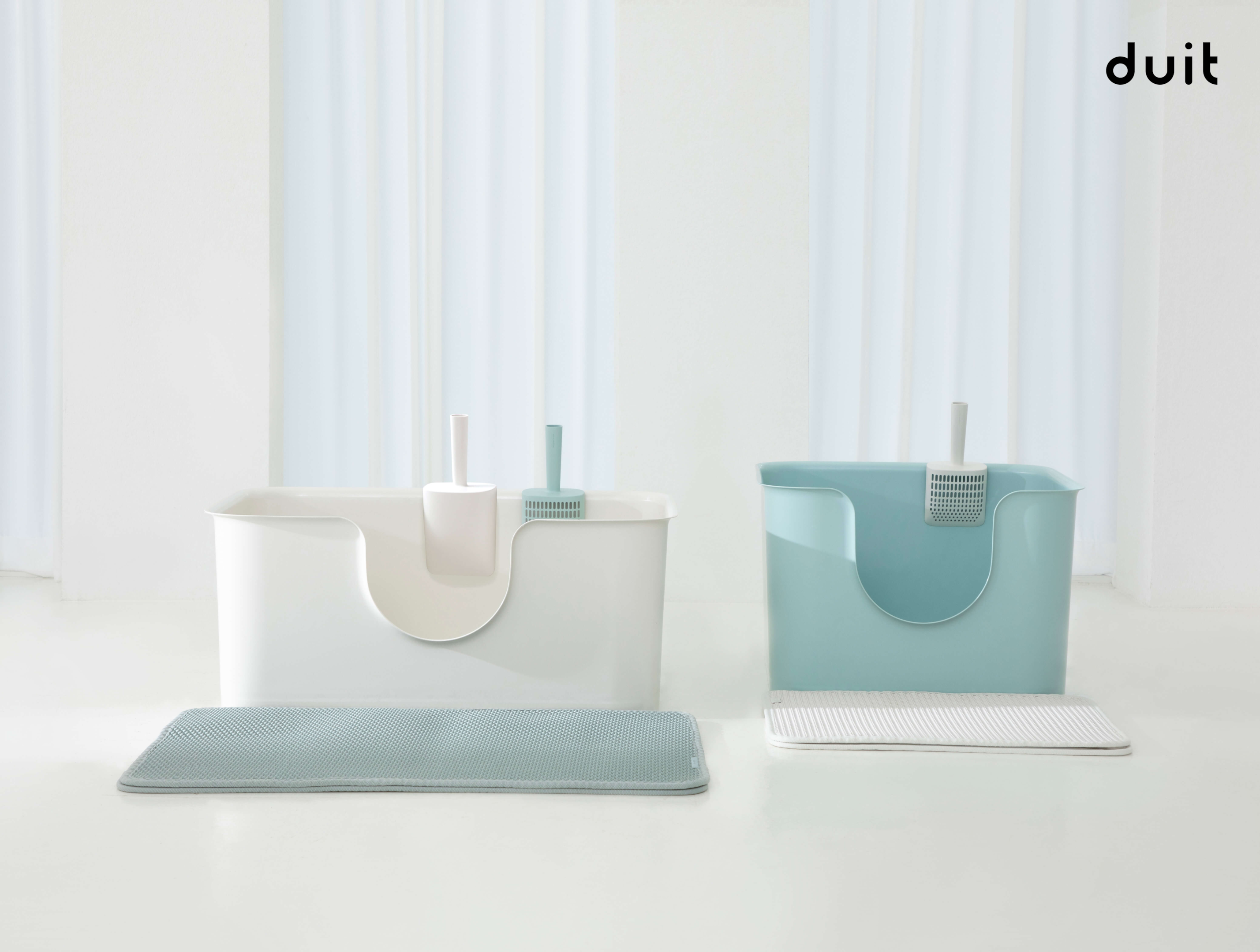 Two different litter boxes next to each other; White and wide litter box is placed next to a teal and square litter box.