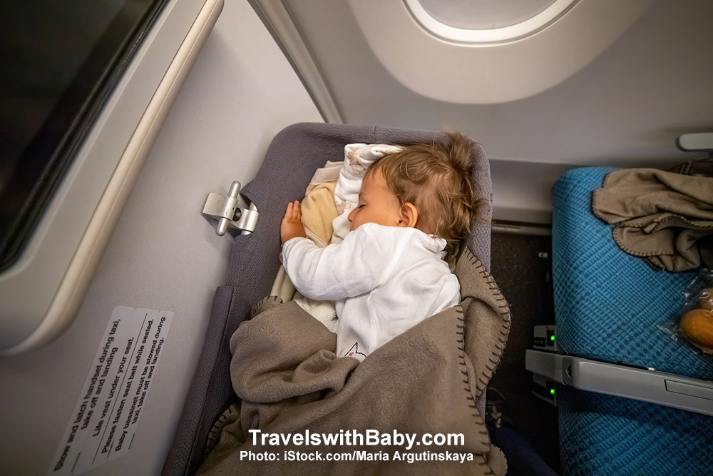 Baby sleeping in airline bassinet on long haul overseas flight.