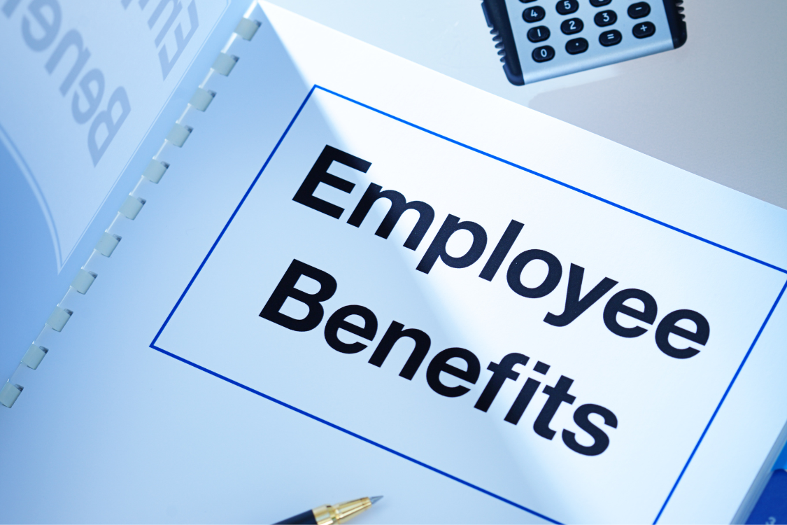 Close-up of an employee benefits binder on a desk with pen and calculator