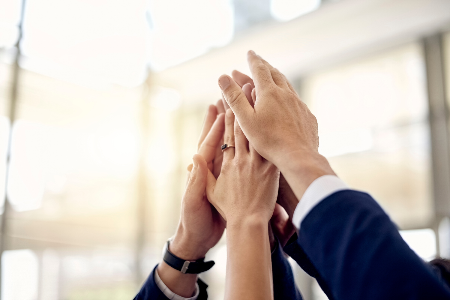 A group of employees with hands showing a hi five, depicting teamwork.