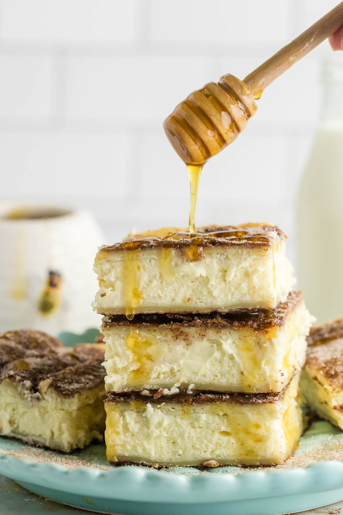 three sopapilla cheesecake bars stacked and being drizzled with honey