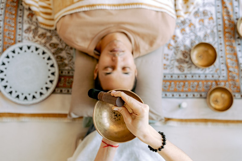 Death practice: Man lying down while someone is using a singing bowl over their head