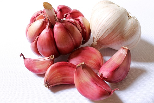 An image of a head of garlic beside garlic cloves on a white background.