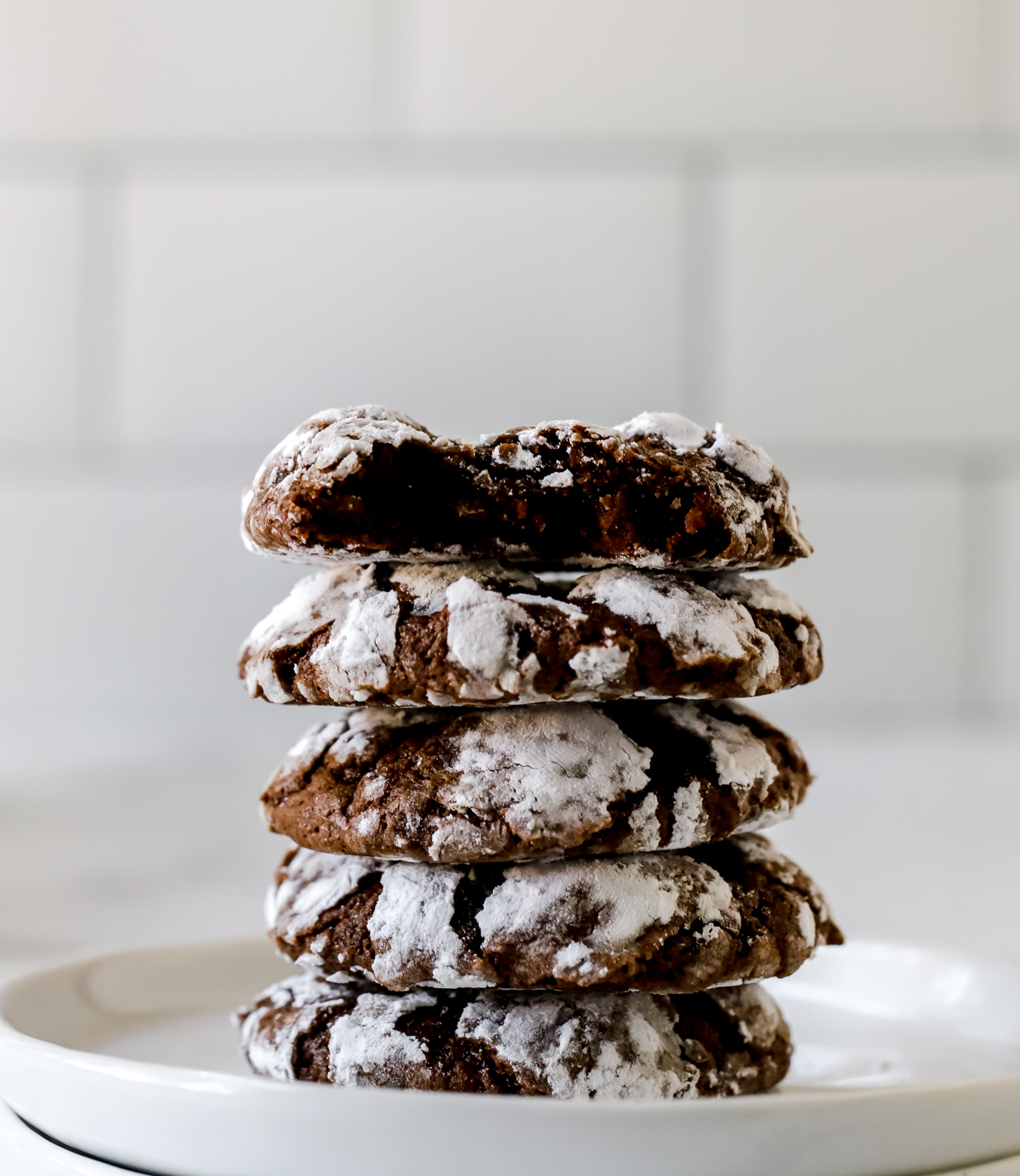 five double chocolate crinkle cookies stacked on white plate