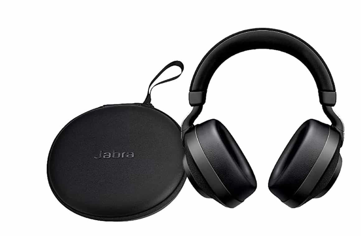 Jabra Elite 85h noise-cancelling headphones sitting next to their black charging case, with the ear cups folded flat and the headband visible. The case has a matte black finish and a Jabra logo on the front. The headphones are black with silver accents and have plush ear cups and a padded headband for comfort.