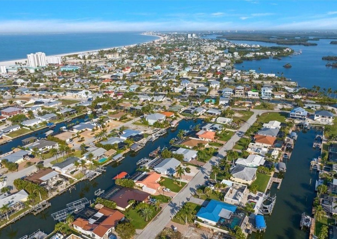 An aerial view of Fairview Isles reveals a scenic canal system that provides direct Gulf access, showcasing the peaceful south end of Fort Myers Beach. The image highlights the beautifully designed homes nestled along the waterways, emphasizing the coastal charm and prime location of this tranquil retreat.