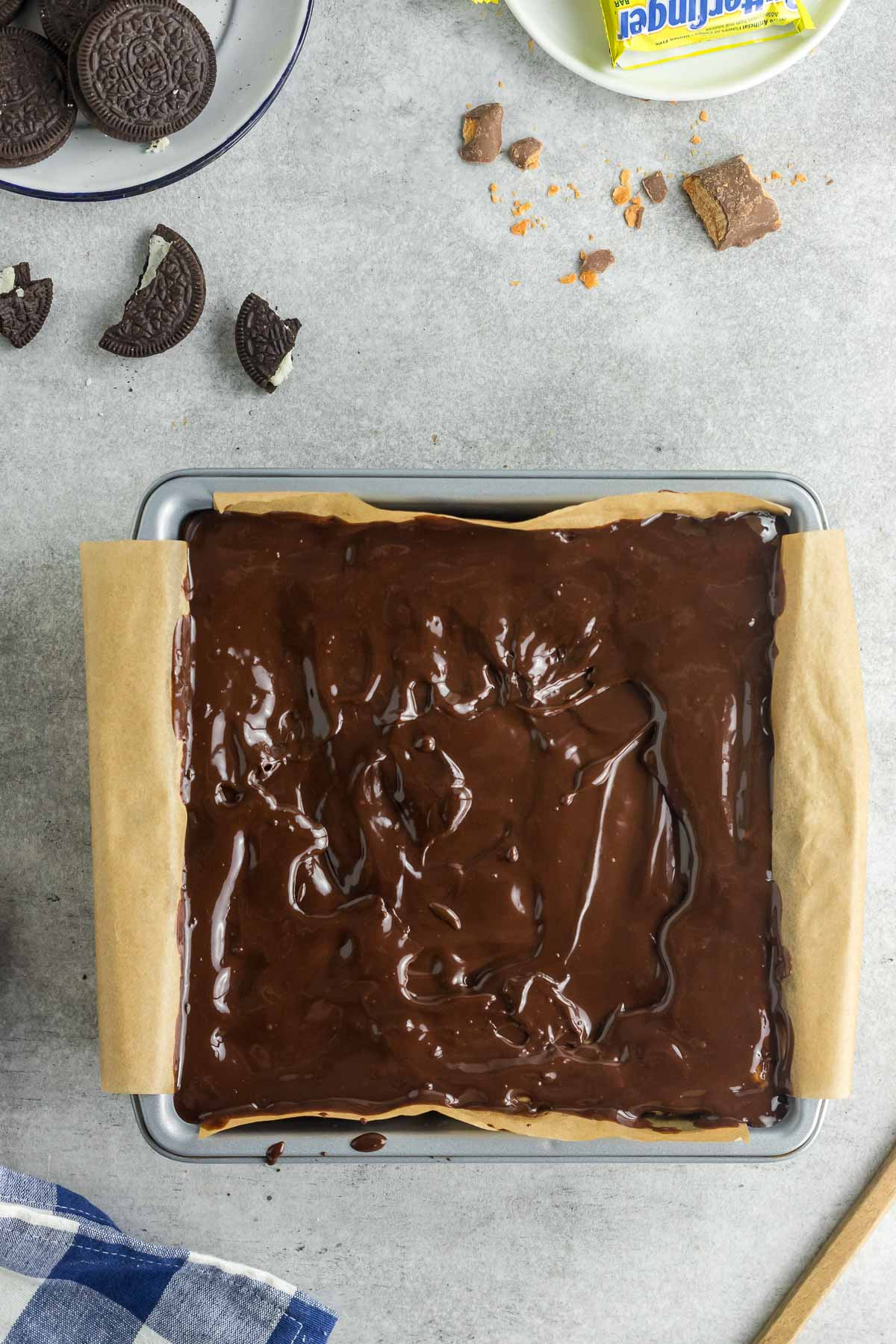 chocolate ganache spread on top of butterfinger cheesecake bars