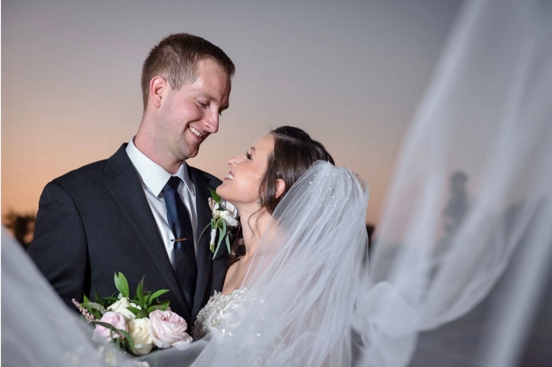 An experienced wedding photographer interacting with a couple during a wedding shoot.