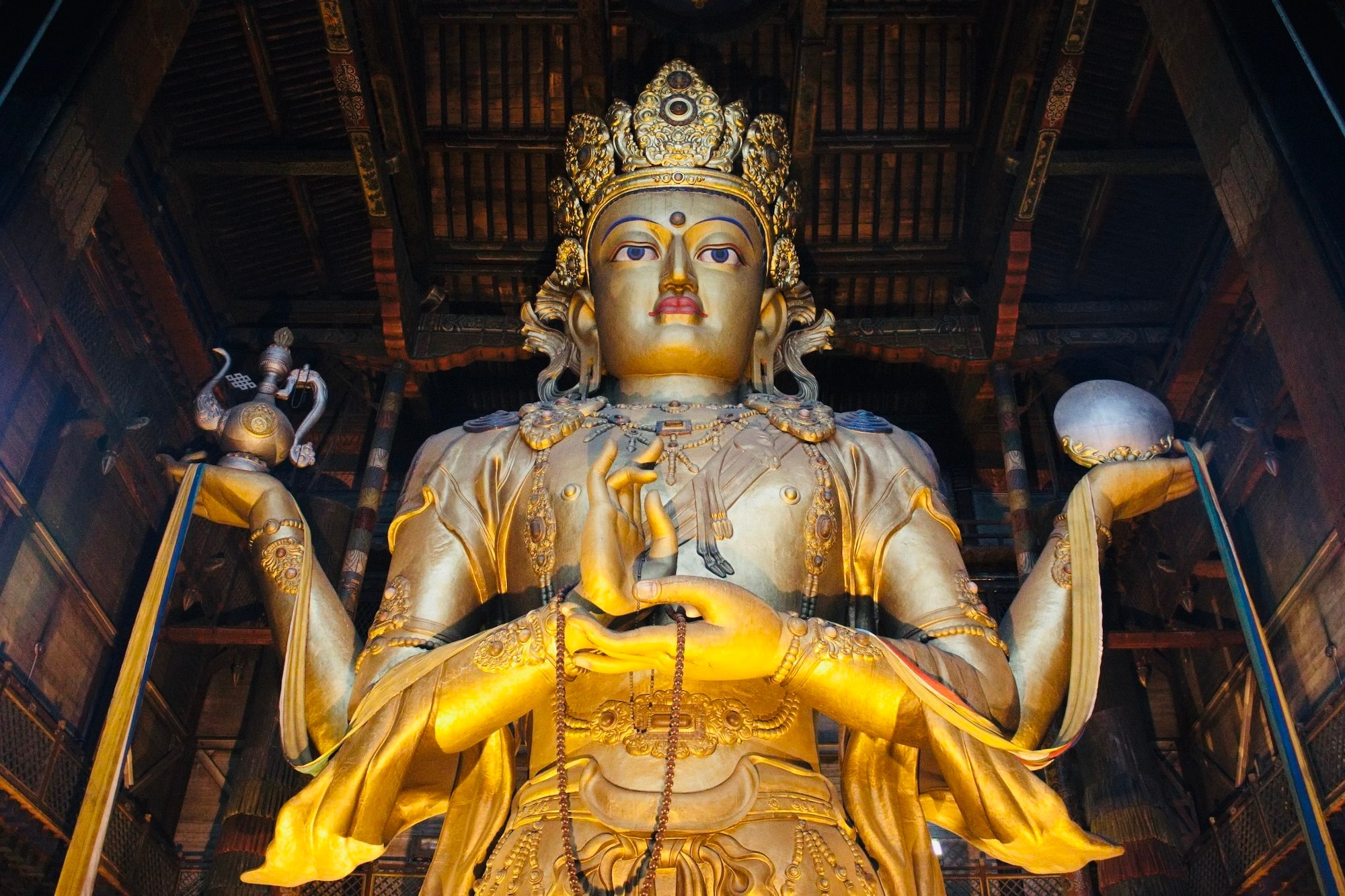 A grand Buddha statue in a Mongolian temple, adorned in gold and intricate details.