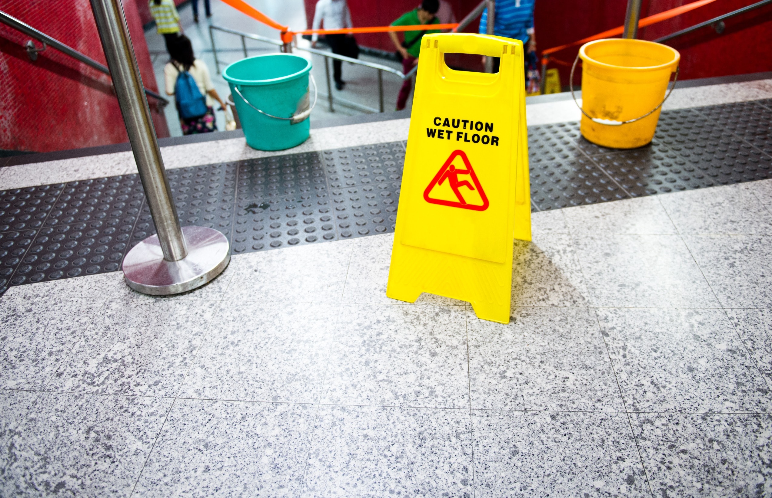A yellow wet floor sign at the top of a set of stairs