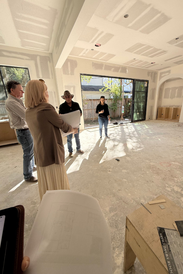 Interior designers walking through a home during early construction framing, reviewing layout and structural elements of a renovation project.