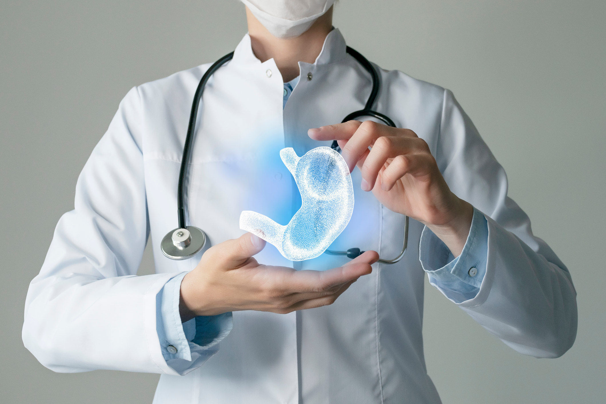 An image of a doctor holding a graphical image of a human stomach. 