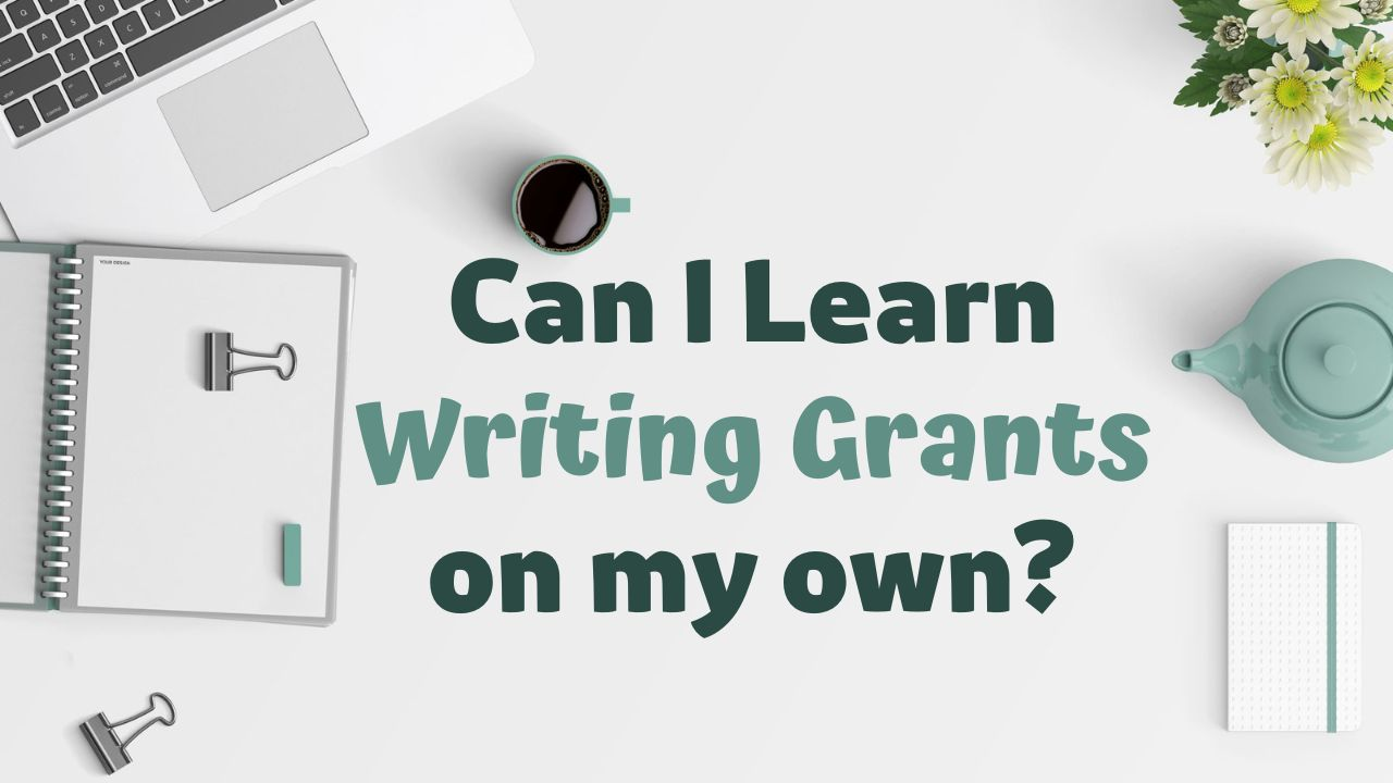 A white office table with various items including a laptop, notebook, coffee mug, pot, paper clip, and a bold green text that reads "Can I learn Grant Writing on my own."