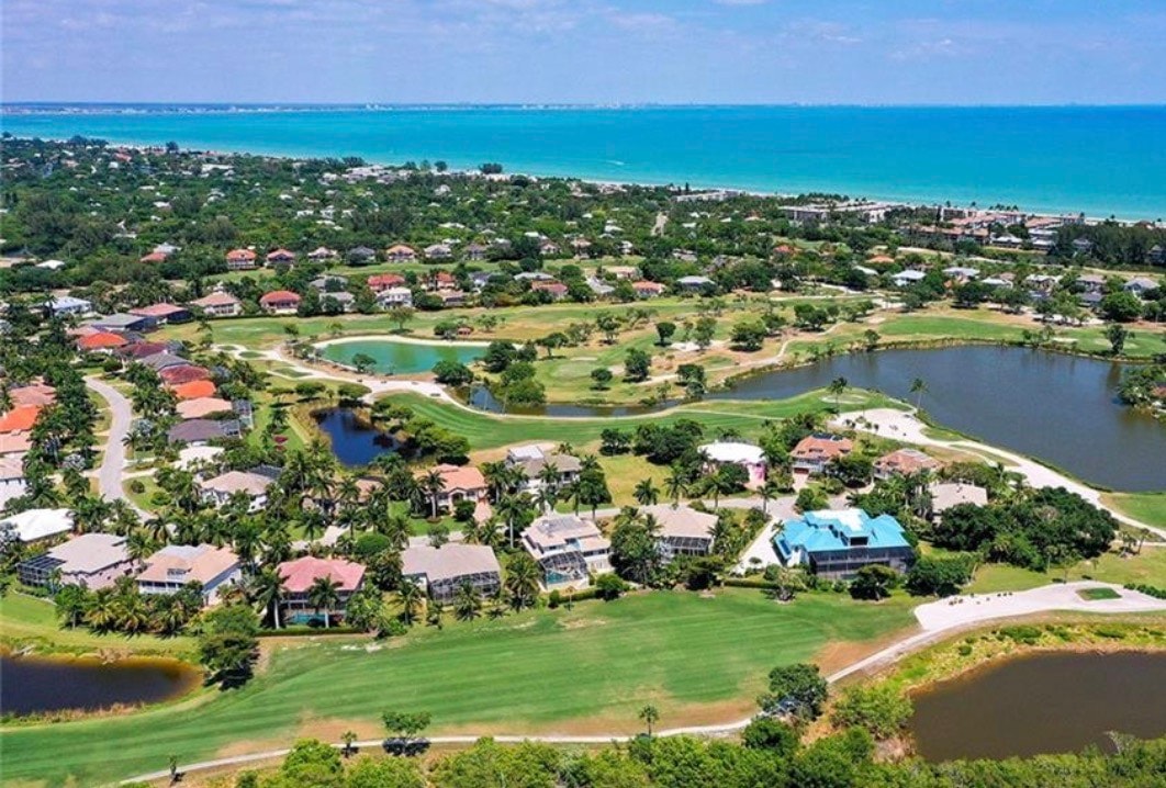 The image depicts a championship golf course gracefully winding around serene water features and lush preserve areas, showcasing the stunning landscape of Sanibel Island. This picturesque setting highlights the luxurious tropical island life, making it a prime location for golf enthusiasts at the Sanibel Island Golf Club.