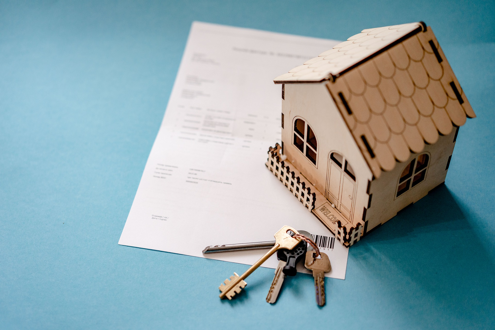 Wooden house with bank statement and keys. 