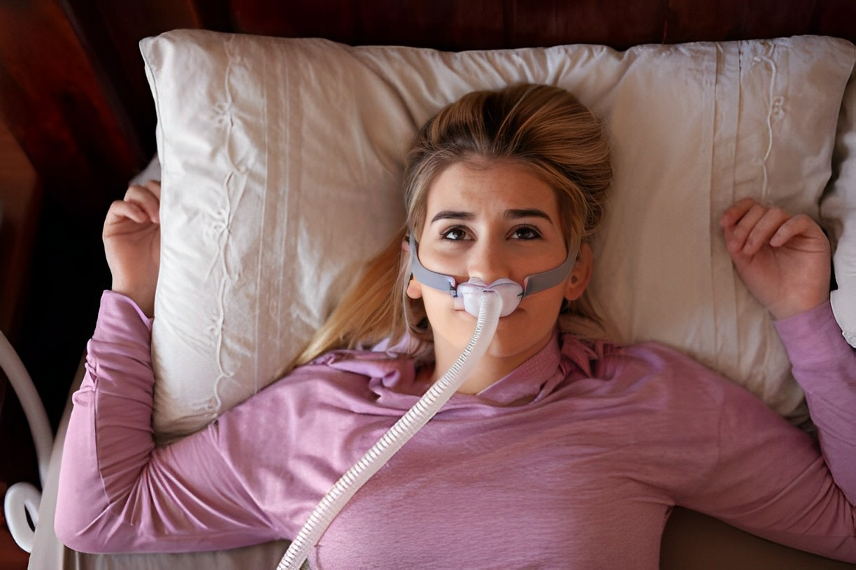 A photo of a woman wearing CPAP headgear looking up