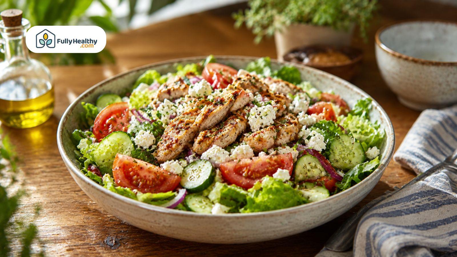Healthy salad bowl with tomatoes, cucumber, grilled chicken, lettuce, and feta cheese.