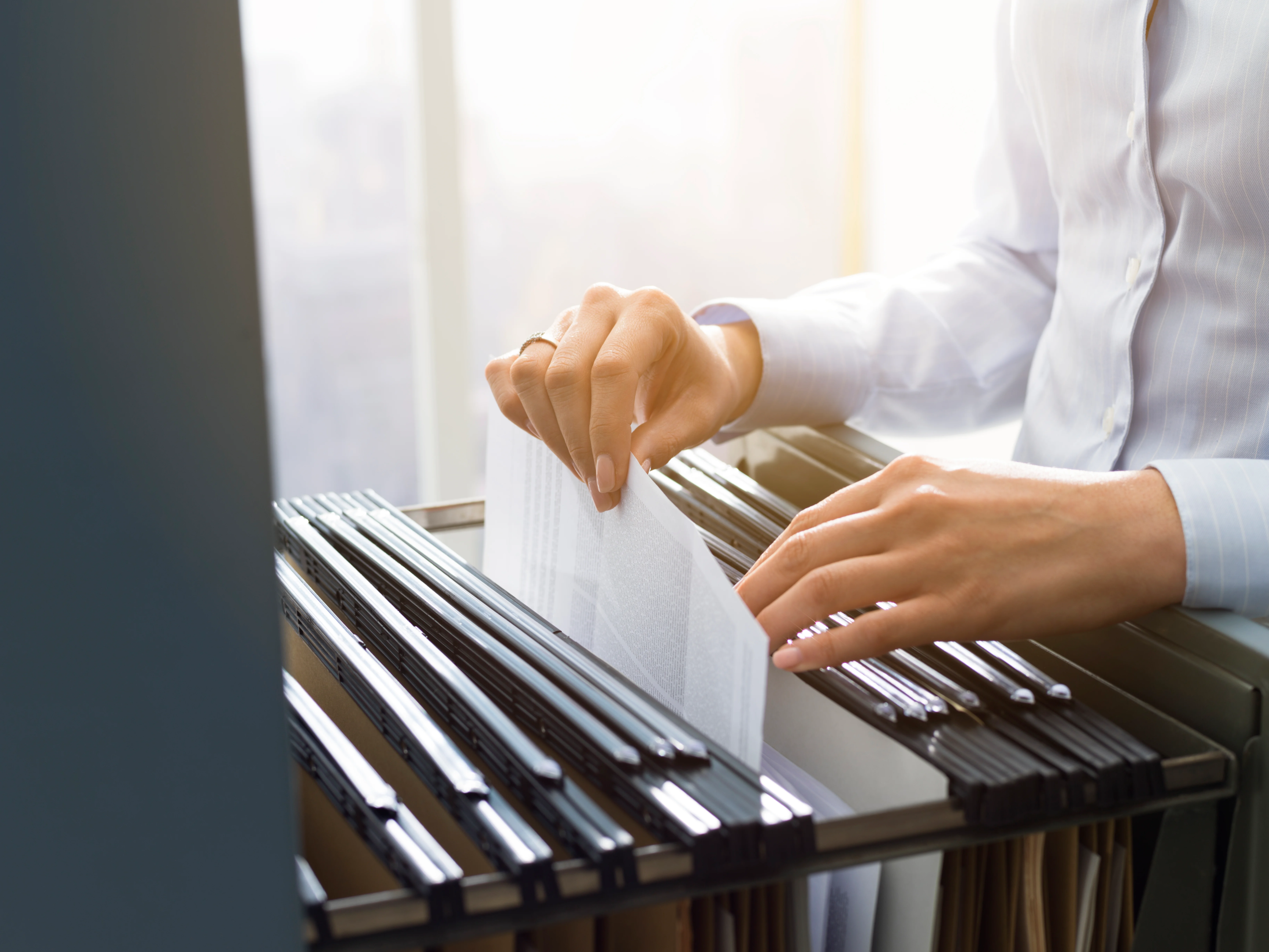 A person holding a stack of documents and a pen