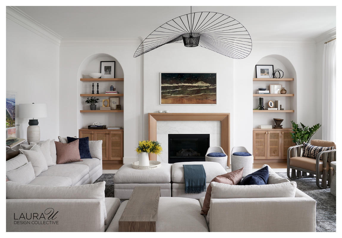 Modern living room with arched built-in bookcases, wood shelving, and a marble fireplace designed by Laura U Design Collective.