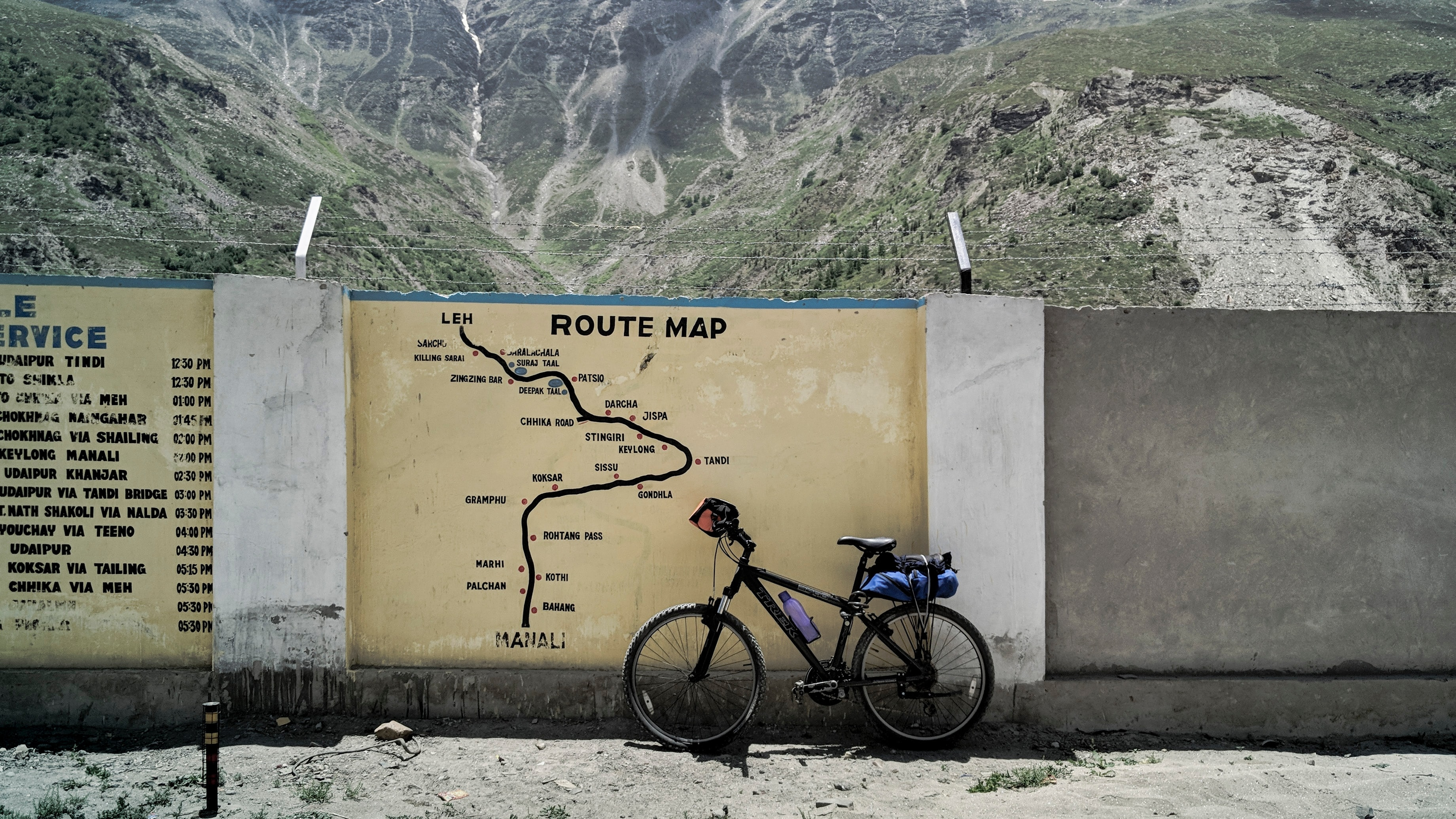 Uma bicicleta encostada num muro com o mapa de uma rota