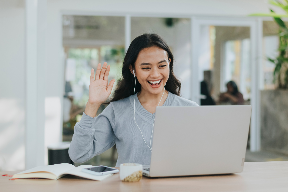 Filipino job applicant smiling and waving during a virtual interview on a laptop
