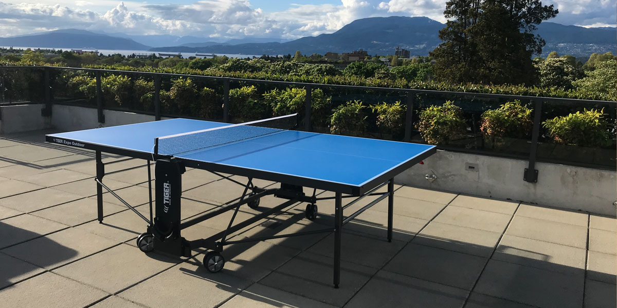 A ping pong table located outside on a deck with a view of mountains in the background.