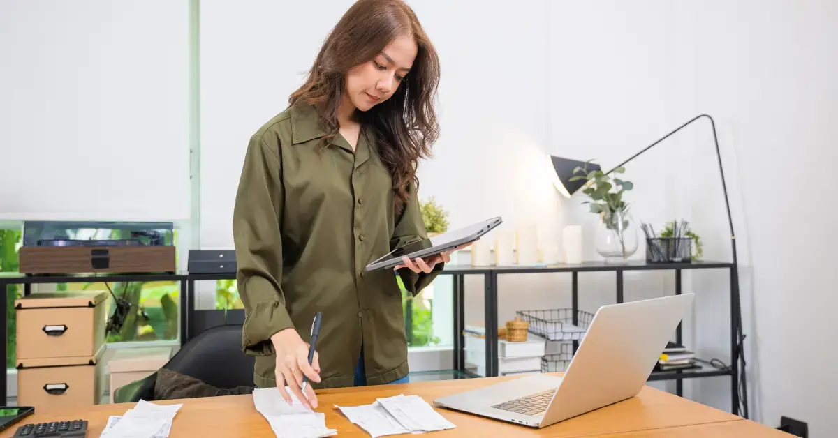 Woman reviewing IRS letter 1058 with tax records and a laptop at her desk.