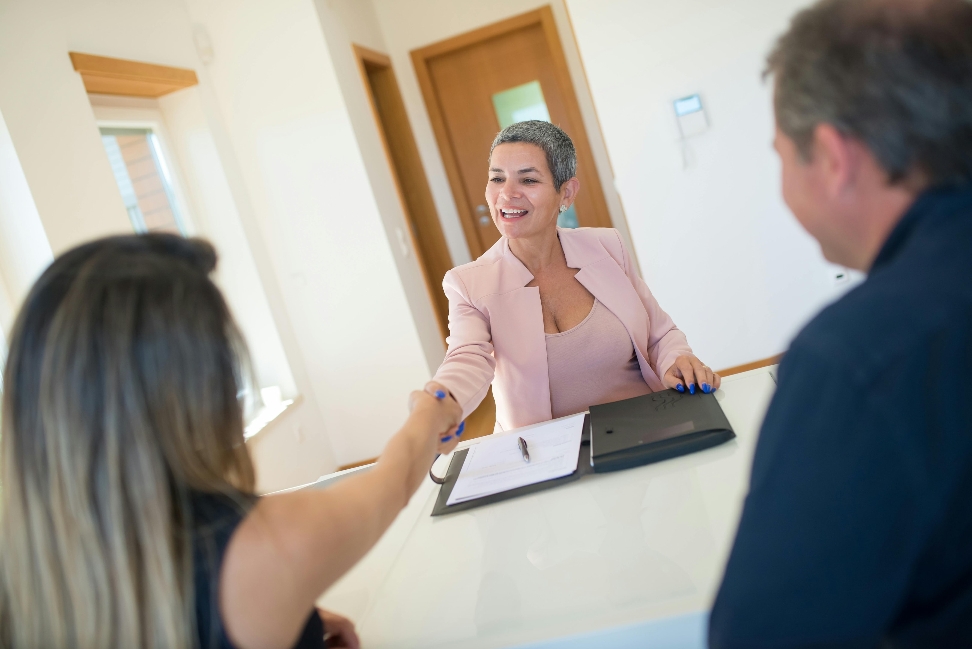 Real estate investor shakes hand of home seller after successful deal.