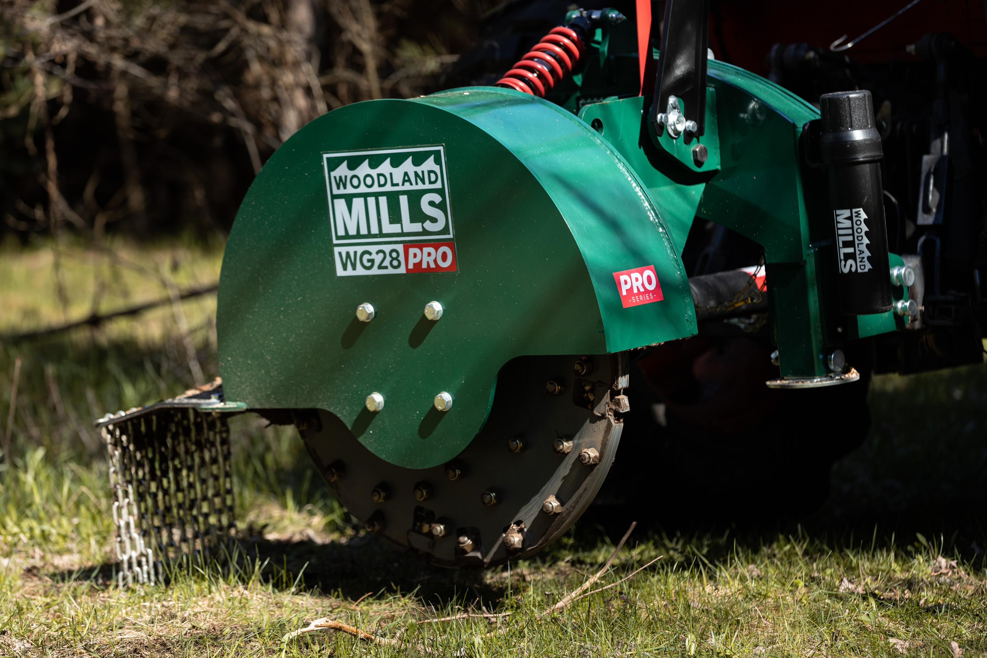 A Woodland Mils WG28 PRO Stump Grinder attached to a tractor in a field.