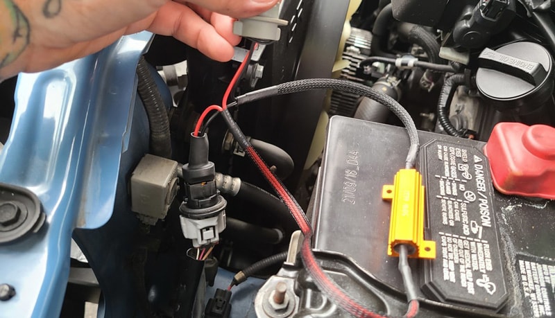 A mechanic inspecting and maintaining a car’s wiring system to prevent hyper-flashing issues