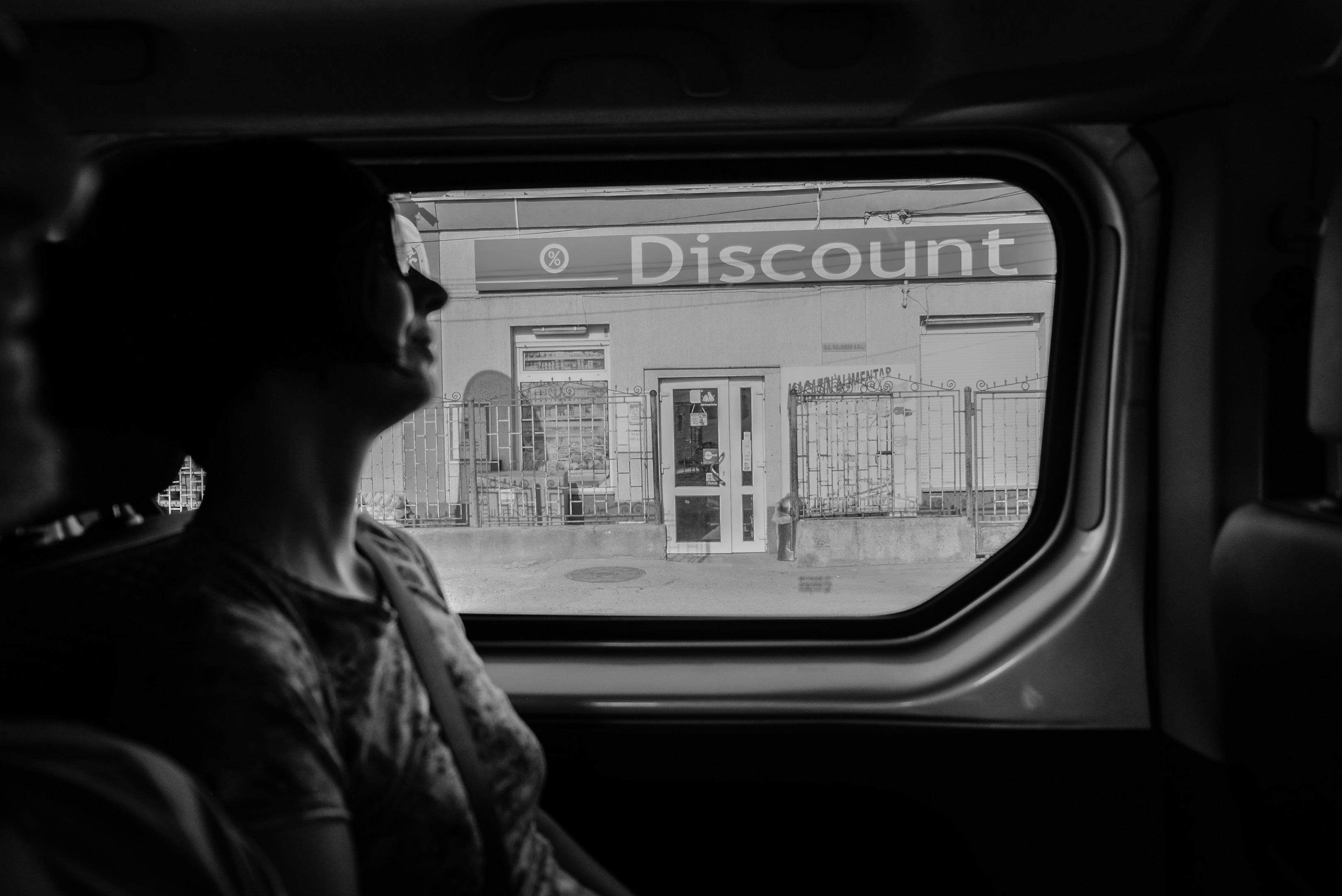 A sign that reads "discount" viewed through the left backseat window of a car. GA auto hauling services.
